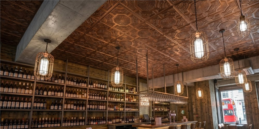 PL02 aged copper ceiling tiles installed above an industrial wine bar with cage pendant lights